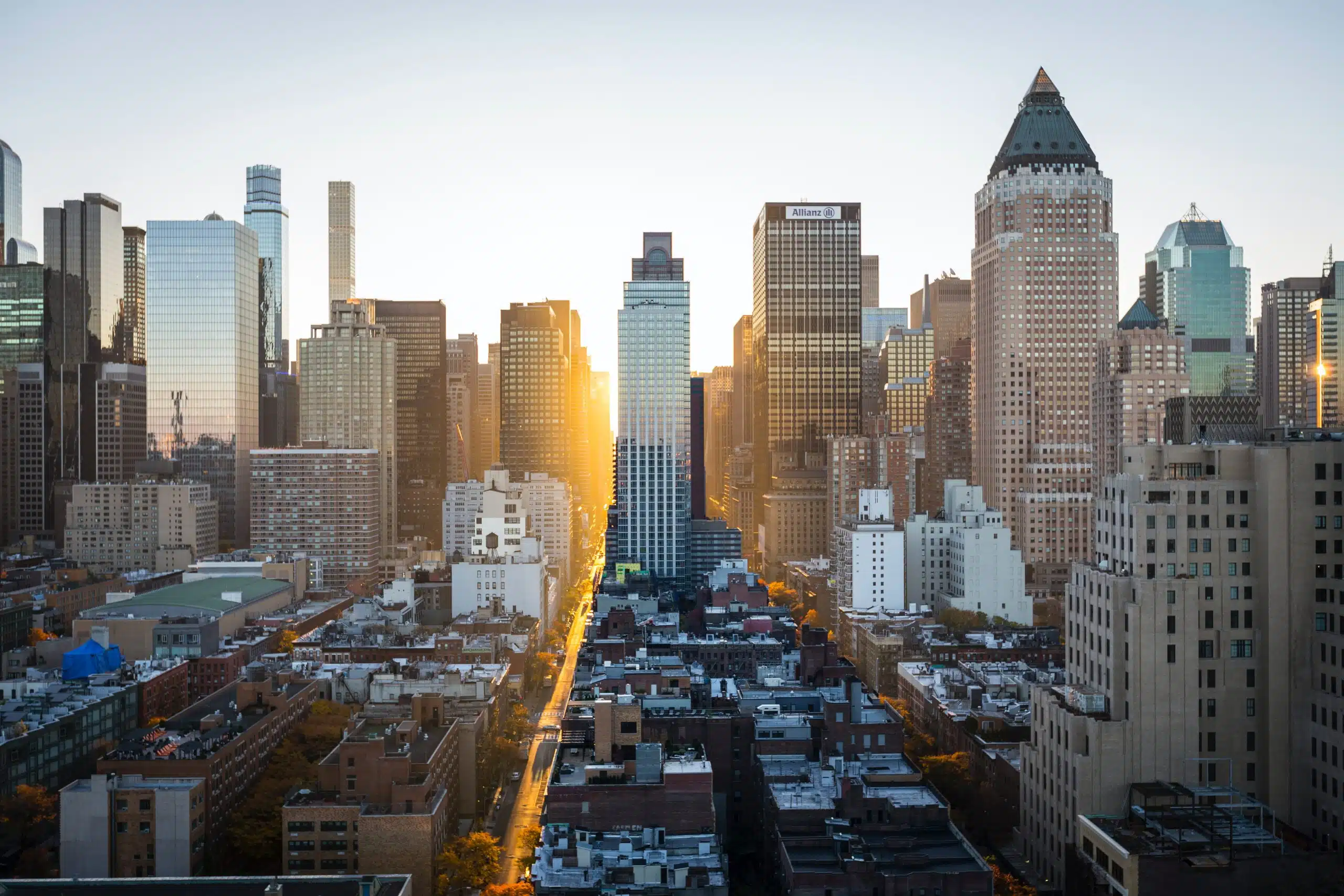 A level view of new york buildings with the sun peaking through.